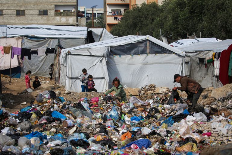 afp_692c03302ab0-1764492080 People sift through a rubbish pile at the Nuseirat camp for displaced Palestinians in the central Gaza Strip on November 29, 2025.