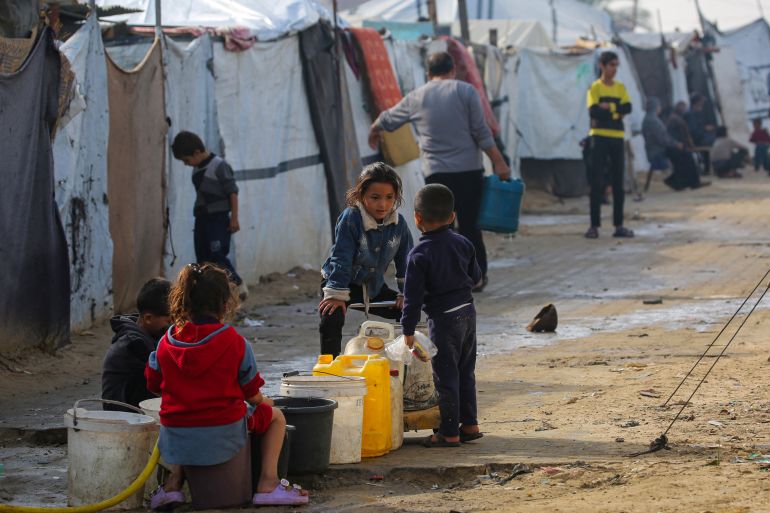 afp_692c03385c95-1764492088 TOPSHOT - Children chat as they fill their containers with water at the Nuseirat camp for displaced Palestinians in the central Gaza Strip on November 29, 2025.