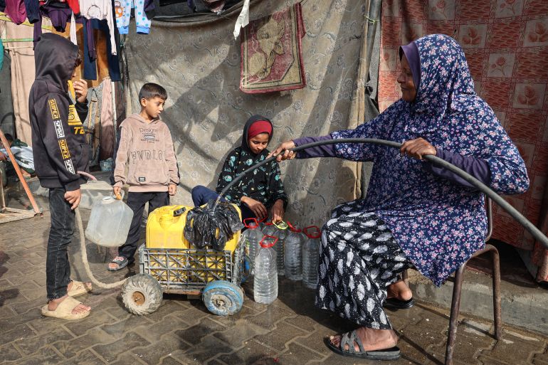 afp_692c034b070b-1764492107 A woman fills containers with water at the Nuseirat camp for displaced Palestinians in the central Gaza Strip on November 29, 2025.