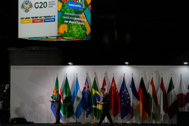 ap_692172529dbce-1763799634 A journalist reports whilst standing next to participating country's flags at the media centre of the G20 Summit in Johannesburg, South Africa, Friday, Nov. 21, 2025. (AP Photo/Themba Hadebe)