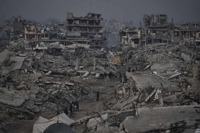 Palestinians walk through widespread devastation in Gaza City on Thursday, Nov. 27, 2025. (AP Photo/Jehad Alshrafi)