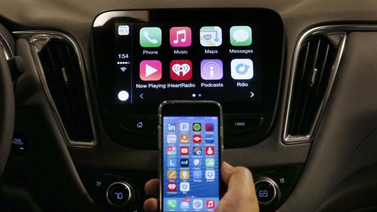 An iPhone is connected to a 2016 Chevrolet Malibu equipped with Apple CarPlay apps, displayed on the car's MyLink screen, top, during a demonstration in Detroit, Tuesday, May 26, 2015. Starting with Chevrolet this summer, many General Motors models will offer Apple’s CarPlay and Google’s Android Auto systems that link smart phones with in-car screens and electronics. (AP Photo/Paul Sancya)