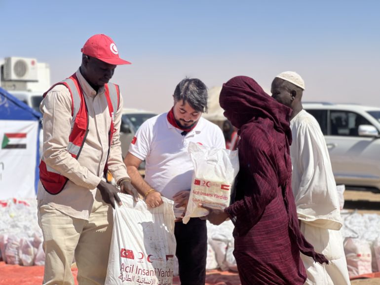 AL DABBAH, SUDAN - NOVEMBER 14: Sudanese people displaced from El-Fasher and other conflict-affected areas receive aid distributed in cooperation with the Turkish Red Crescent and the Sudanese Red Crescent at the El-Afadh camp in Al Dabbah, in Sudan’s Northern State, on November 14, 2025. Tens of thousands of Sudanese have been displaced due to clashes in the region following the fall of the city of El-Fasher, in western Sudan, to the Rapid Support Forces (RSF) on October 26. ( Stringer - Anadolu Agency )