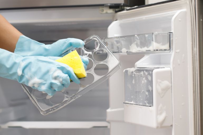Employees use a cloth to clean the refrigerator.