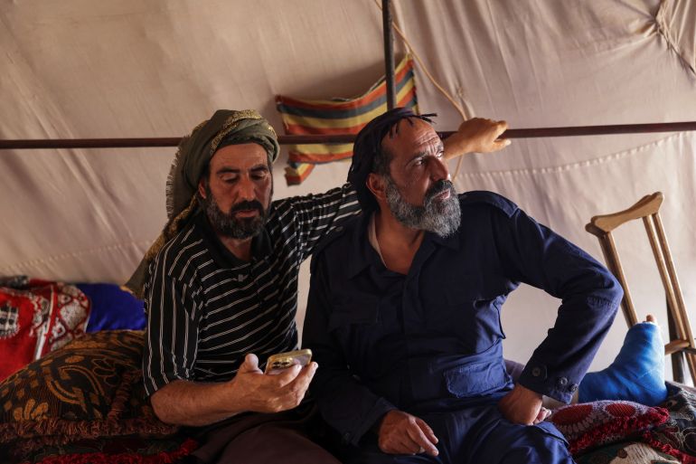 reuters_690f428c-1762607756 Faisal Sbeih, 46, and his brother Nasri, 42, who fled sectarian fighting in Syria's Sweida province, sit inside their tent in the Daraa countryside, Syria, August 8, 2025. REUTERS/Khalil Ashawi