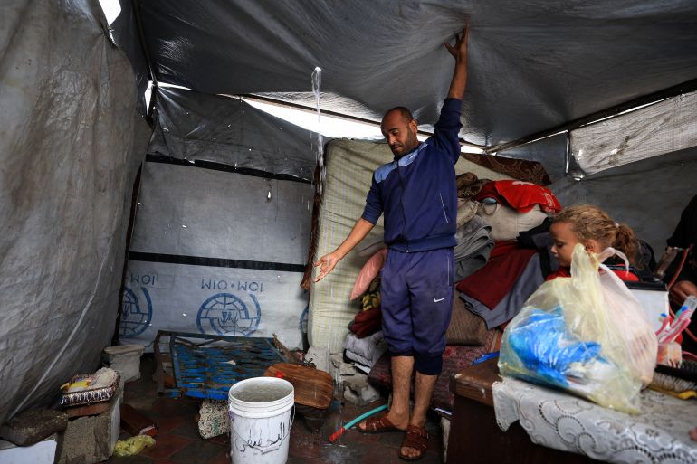 reuters_69197faf-1763278767 A Palestinian man removes water from the roof top of a tent on a rainy day, during a ceasefire between Israel and Hamas, in Gaza City, November 14, 2025. REUTERS/Dawoud Abu Alkas