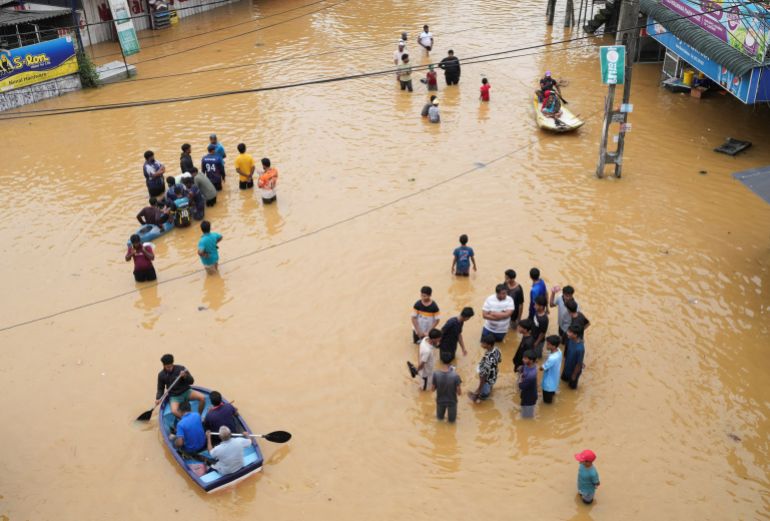 People use boats to move on a flooded street as others stand around, following heavy rainfall in Malwana, Sri Lanka, November 29, 2025. REUTERS/ Thilina Kaluthotage