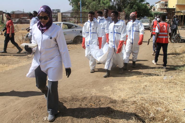 Members of the Red Crescent and others working for the authorities carry away a body bag as the exhumation and transfer of bodies from emergency burial sites inside schools, are taken to public cemeteries for burial, in the capital Khartoum on December 8, 2025. (Photo by Ebrahim Hamid / AFP)
