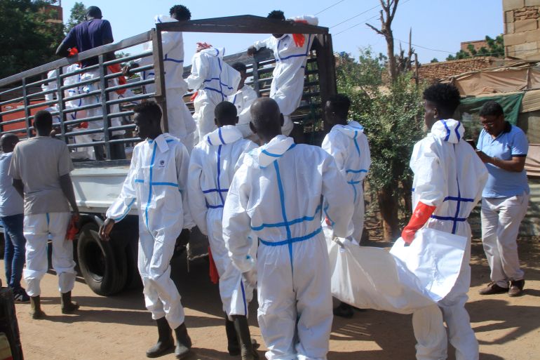 Employees working for the authorities load a body bag into the back of a lorry as bodies are dug up from an emergency burial site inside a school, to be buried in public cemeteries, in the capital Khartoum on December 8, 2025. (Photo by Ebrahim Hamid / AFP)