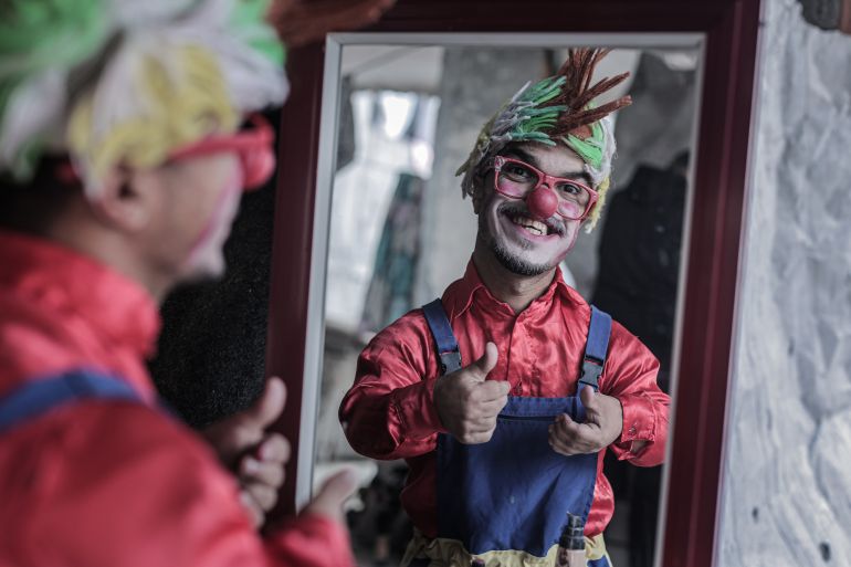 DEIR AL BALAH, GAZA - DECEMBER 13: Ahmed Mahmud Kamil Abu Seker, a 28-year-old resident of Bureij Refugee Camp who volunteers as a clown to bring smiles to children's faces, prepares himself in front of a mirror before meeting with the children in Deir al-Balah, Gaza on December 13, 2025. Despite losing his entire family in the war, Seker works as a clown to make children laugh, and despite all the difficulties, he tries to hold on to life in order to bring a smile to children's faces. ( Fadel A. A. Almaghari - Anadolu Agency )