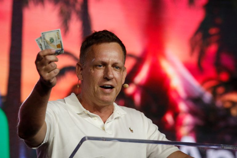 84-1764777815 MIAMI, FLORIDA - APRIL 7: Peter Thiel, co-founder of PayPal, Palantir Technologies, and Founders Fund, holds hundred dollar bills as he speaks during the Bitcoin 2022 Conference at Miami Beach Convention Center on April 7, 2022 in Miami, Florida. The worlds largest bitcoin conference runs from April 6-9, expecting over 30,000 people in attendance and over 7 million live stream viewers worldwide. Marco Bello/Getty Images/AFP (Photo by Marco Bello / GETTY IMAGES NORTH AMERICA / Getty Images via AFP)