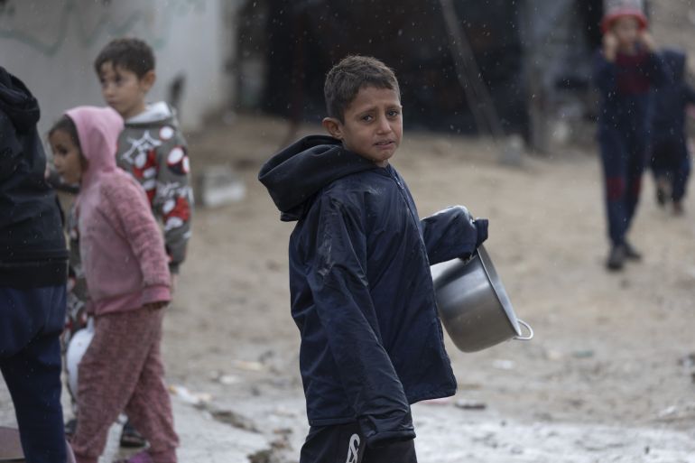 87-13-1765870143-1 GAZA CITY, GAZA - DECEMBER 15: A child carries a pan as Palestinians displaced by Israeli attacks struggle to carry out their daily lives under harsh conditions in makeshift tents in Gaza City, Gaza on December 15, 2025. Heavy rainfall and strong storms affect the Gaza Port area in western Gaza City, damaging tents where displaced Palestinians take shelter. Adverse weather conditions further exacerbate the hardships faced by displaced Palestinians living under severe humanitarian conditions. ( Mahmoud Abu Hamda - Anadolu Agency )