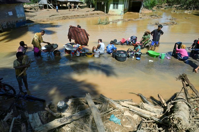 afp_692ff0ac2e5c-1764749484 Villagers wash their clothes in a puddle after their village was hit by a flash flood at Tukka village, Central Tapanuli, North Sumatra province, on December 3, 2025.