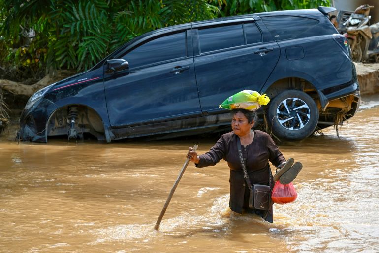 afp_692ff1c10c9f-1764749761 A woman wades through the floodwater in the aftermath of flash floods at Tukka village, Central Tapanuli, North Sumatra province, on December 2, 2025.