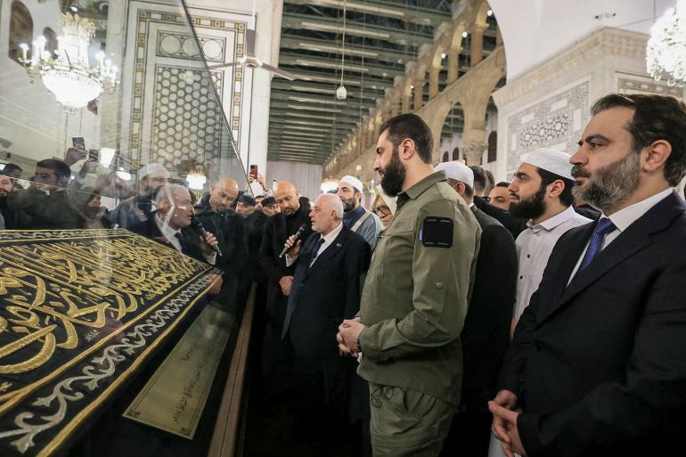 This handout photograph released by the official Syrian Arab News Agency (SANA) on December 8, 2025, shows Syria's President Ahmed al-Sharaa (3rd R) and Syrian Minister of Foreign Affairs and Expatriates Asaad Al-Shaibani (R) attending prayers at Umayyad Mosque in Damascus for the anniversary of the ousting of longtime ruler Bashar al-Assad.