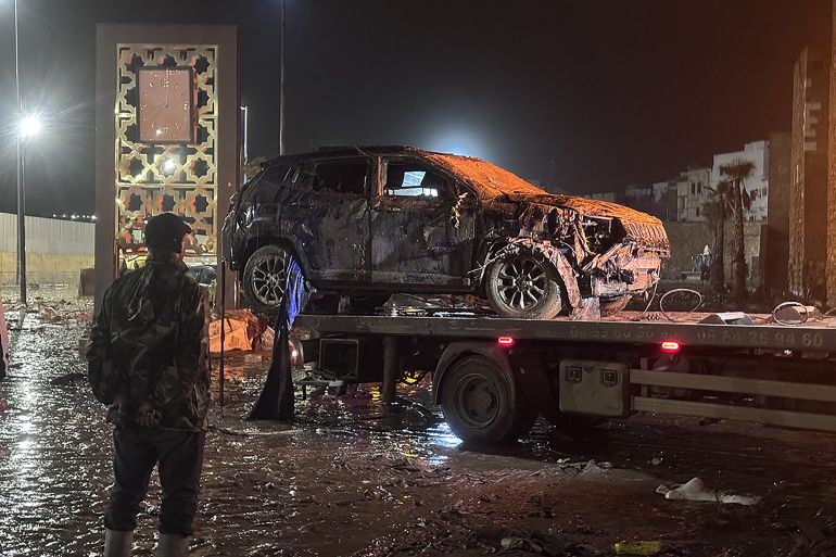 afp_693fb9feae34-1765784062 A man watches a car damaged by a flash flood being removed in Safi on December 14, 2025.
