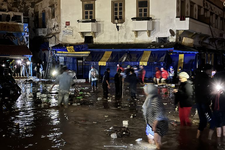 afp_693fba02d209-1765784066 People wade through a square after a flash flood in Safi on December 14, 2025.