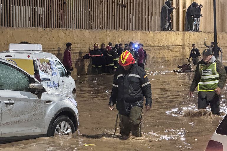 afp_693fba12c153-1765784082 People wade through a street after a flash flood in Safi on December 14, 2025.
