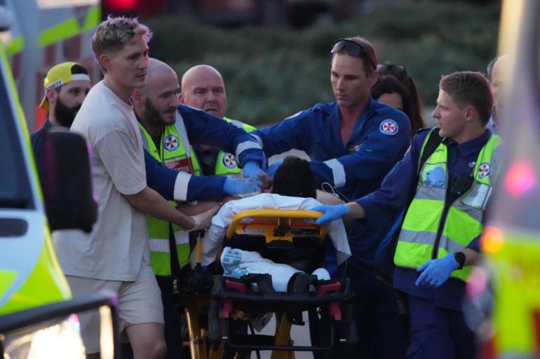 ap25348331370589-1765706296 Emergency workers transport a person on a stretcher after a reported shooting at Bondi Beach, in Sydney, Sunday, Dec. 14, 2025. (AP Photo/Mark Baker)