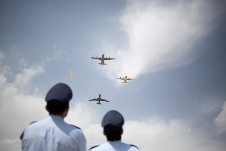Two Israeli Air Force pilots watch the C-130J Super Hercules military aircraft, top, as it lands during an unveiling ceremony upon its arrival in Nevatim Air Force base near Beersheba , Southern Israel, Wednesday, April 9, 2014. The U.S. made Lockheed-Martin C-130 line of transport aircraft will join the Israel Air Force’s fleet. (AP Photo/Ariel Schalit)