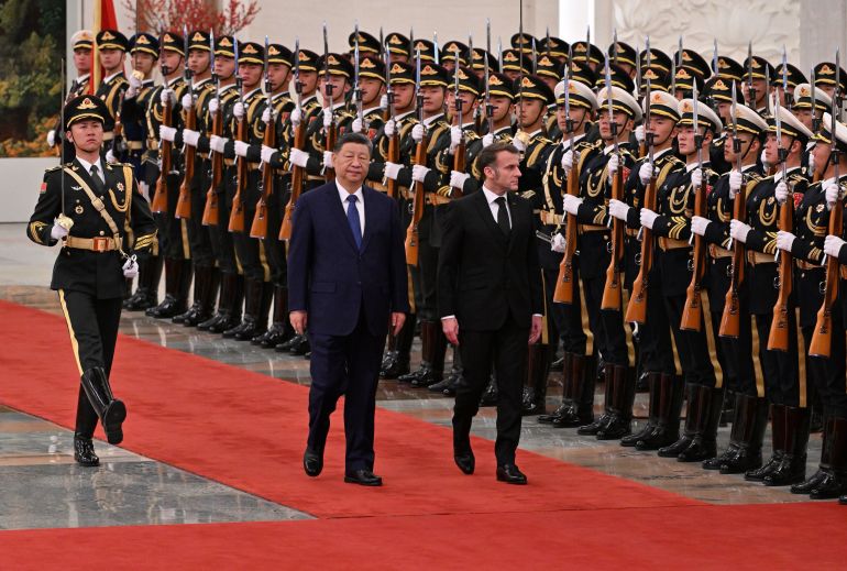 ap_693119b634003-1764825526 France's President Emmanuel Macron, right, and China's President Xi Jinping, center, review honour guards during a state visit at the Great Hall of the People in Beijing Thursday, Dec. 4, 2025. (Adek Berry/Pool Photo via AP)