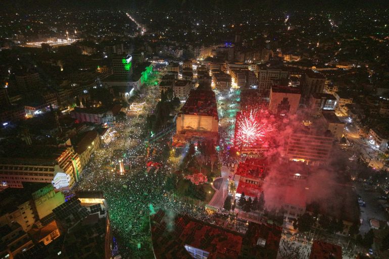 ap_6937e1044bf70-1765269764 Fireworks and light beams illuminate the sky as people fill Clock Square in central Homs, western Syria, Monday, Dec. 8, 2025, to mark the first anniversary of the ousting of the Bashar Assad regime. (AP Photo/Omar Albam)