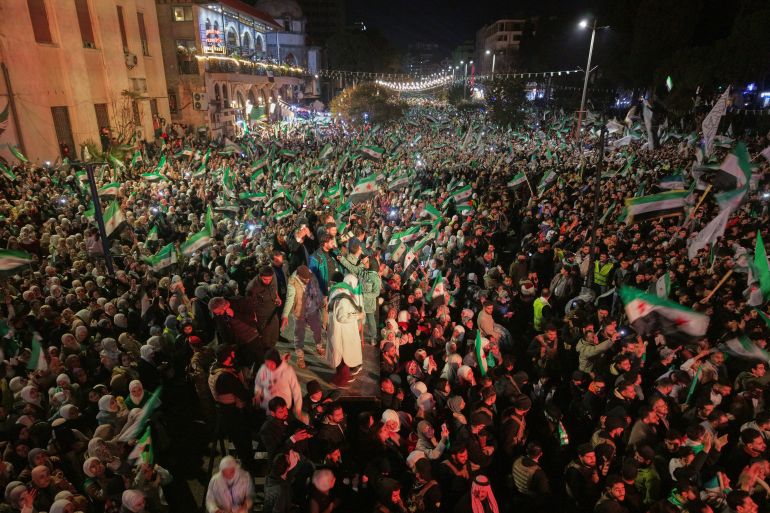 ap_6937e1244706b-1765269796 People fill Clock Square to mark the first anniversary of the ousting of the Bashar Assad regime. in Homs, western Syria, Monday, Dec. 8, 2025.(AP Photo/Omar Albam)