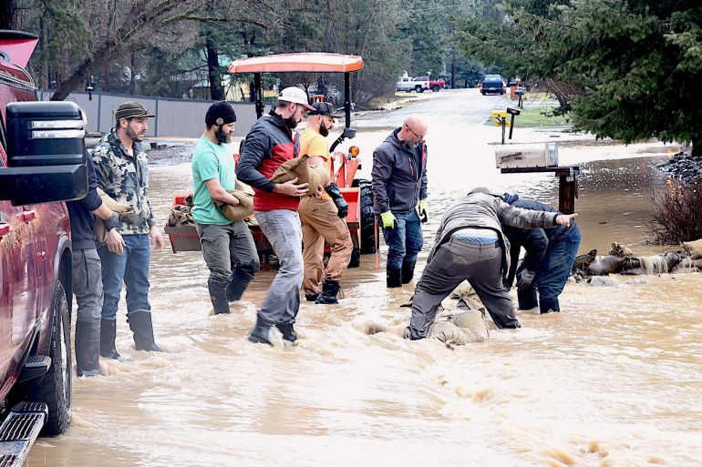 ap_693bc88824cdb-1765525640 Volunteers place sandbags where a creek flooded south of Libby, Mont., Thursday, Dec. 11, 2025. (Scott Shindledecker/The Western News via AP)