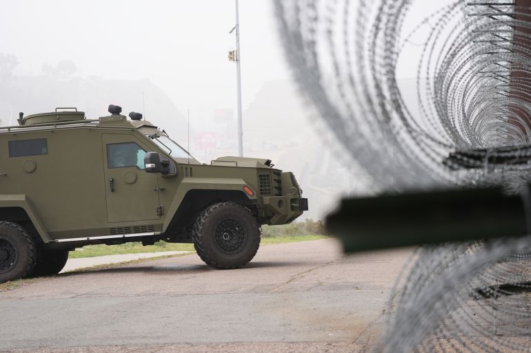 ap_693e88cdd72f3-1765705933 An armored vehicle sits near a news conference with White House border czar Tom Homan along the border with Mexico, Saturday, Dec. 13, 2025, in San Diego. (AP Photo/Gregory Bull)