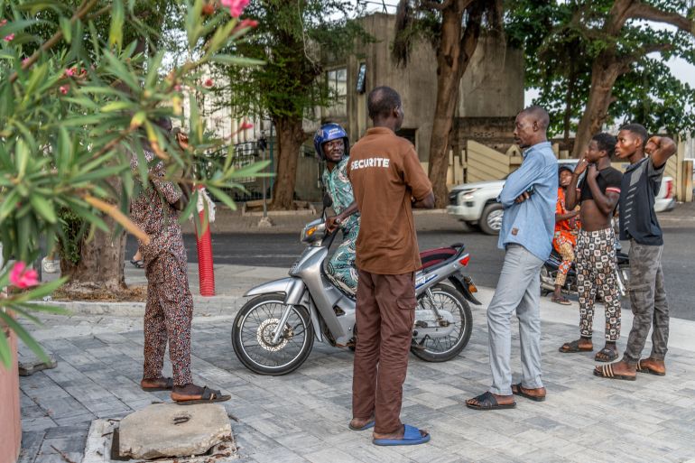 epa12577772 A group of men chat in the street near the Office of Benin Radio and Television Diffusion in Cotonou, Benin, 07 December 2025. The Economic Community of West African States (ECOWAS) ordered the deployment of its Standby Force to Benin following an unsuccessful coup attempt by a group of soldiers, as described by Benin’s president, Patrice Talon. EPA/STRINGER