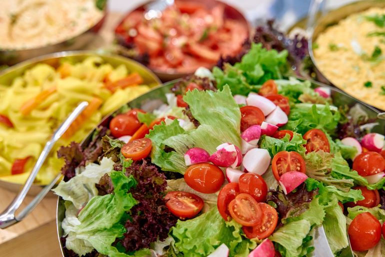 A Colorful Display of Fresh Salads Featuring Vibrant Greens, Cherry Tomatoes, and Radishes in an Abundant Gourmet Setting for a Health-Centric Gathering