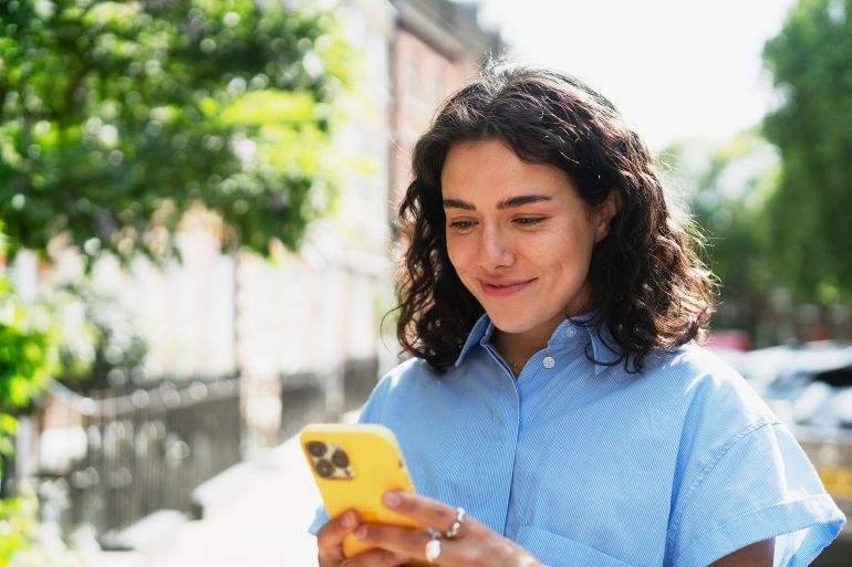 Woman using smart phone, smiling - stock photo