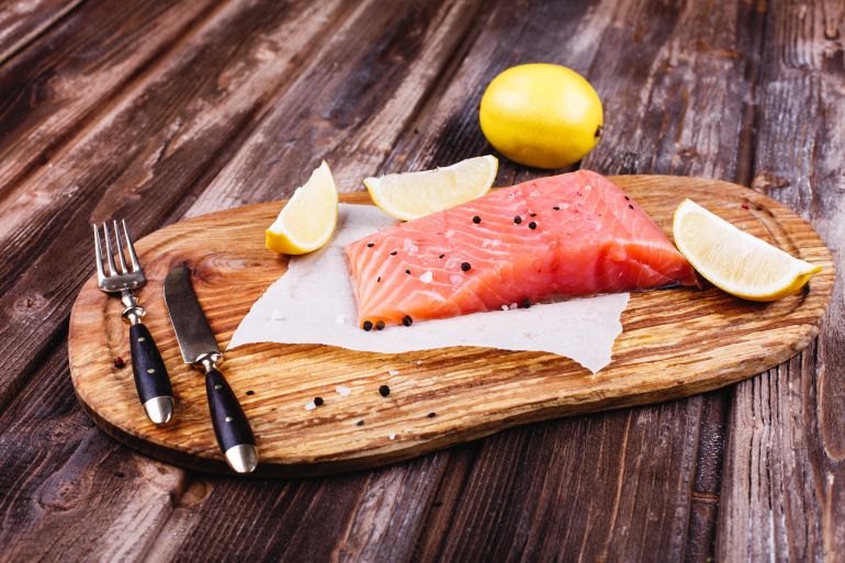 pic-5544-1765220944 التونة أم السلمون.. أي منهما يناسب أسلوب حياتك؟ Healthy and fresh food. Raw salmon served with lemons and knives on wooden board المصدر: فريبك