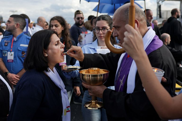 reuters_692ebefd-1764671229 A woman receives Holy Communion as she attends the Holy Mass at the Waterfront, during Pope Leo XIV's first apostolic journey, in Beirut, Lebanon December 2, 2025. REUTERS/Khalil Ashawi