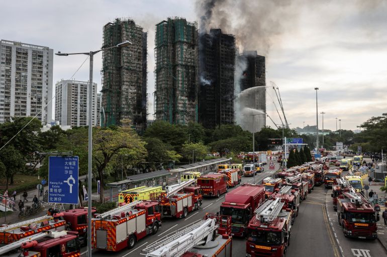 Fire trucks gather in front of Wang Fuk Court housing complex as flames and thick smoke rise from multiple residential blocks during a major fire, in Tai Po, Hong Kong, China, November 27, 2025. REUTERS/Tyrone Siu SEARCH