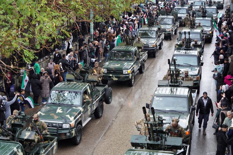 Syrians gather along a street during a military parade, as they mark the first anniversary of Bashar al-Assad's fall, in Latakia, Syria December 8, 2025. REUTERS/Karam al-Masri