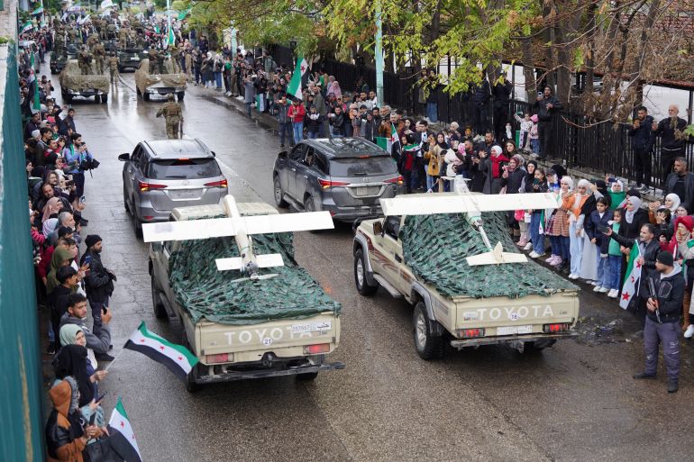 Syrians gather along a street during a military parade, as they mark the first anniversary of Bashar al-Assad's fall, in Latakia, Syria December 8, 2025. REUTERS/Karam al-Masri