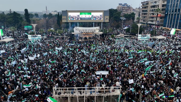 reuters_6937e1b1-1765269937 A drone view shows people gathering during a protest to mark the first anniversary of Bashar al-Assad's fall, in Aleppo, Syria December 8, 2025. REUTERS/Mahmoud Hassano