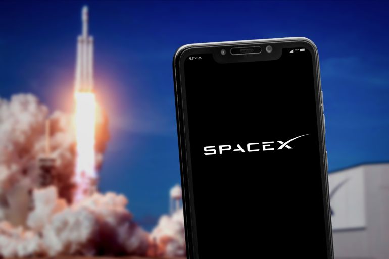shutterstock_2154576713-1762070410 Cali, Colombia - May 6 2022: "SpaceX" logo on the smartphone screen and launch of a rocket at the blurred background. SpaceX is a space transportation and aerospace manufacturer.