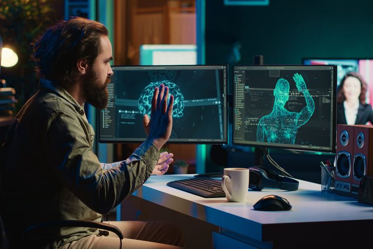 Self aware AGI AI gaining humanoid form inside cyberspace, waving hand, shocking man while drinking coffee. Artificial intelligence becoming sentient, flustering admin spamming keyboard, camera A; Shutterstock ID 2448483059; purchase_order: aj; job: ; client: ; other: