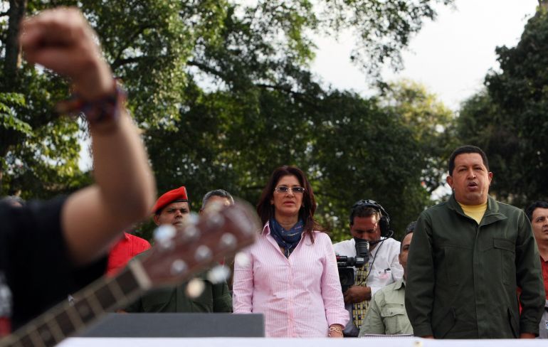Venezuelan President Hugo Chavez (R) and the president of the National Assembly Cilia Flores (L) sing the national anthem on February 19, 2009 in Catia, a poor neigborhood west of Caracas, before the handing in of the minutes of the constitutional amendment. Chavez enacted Thursday the amendment approved Sunday in a referemdum, which will allow indefinite re-election in Venezuela. AFP PHOTO/Pedro REY (Photo by PEDRO REY / AFP)