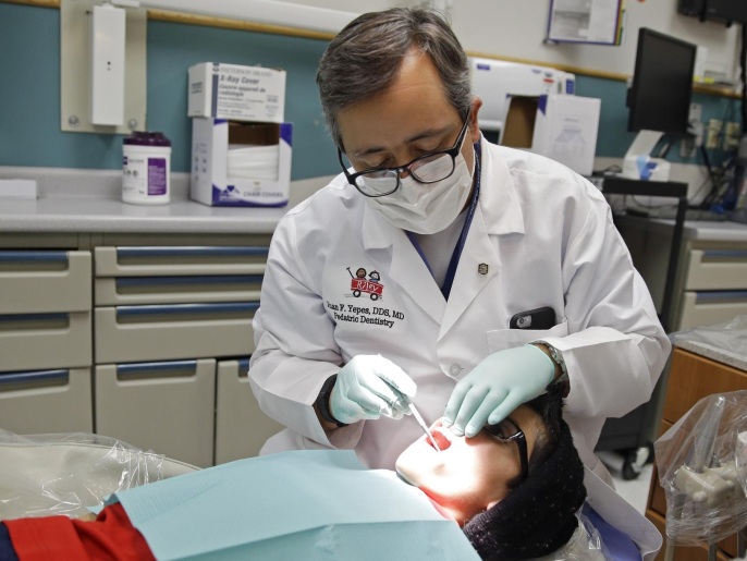 In this Friday, Jan. 22, 2016 photo, Dr. Juan Fernando Yepes, a dentist at the Riley Hospital for Children Department of Pediatric Dentistry, checks the teeth of Justin Perez, 11, during an office visit in Indianapolis. Medicaid covers dental care for an estimated 37 million children from low-income families. The state and federal Medicaid program varies by state, but there are national shortages of dentists who participate. (AP Photo/Michael Conroy)