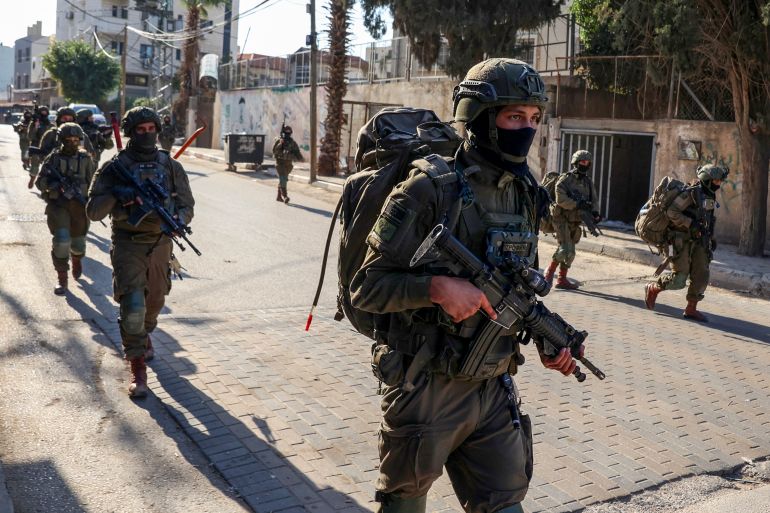 Israeli soldiers walk during a military operation in the town of Qalqiya, in the occupied West Bank on December 4, 2025.