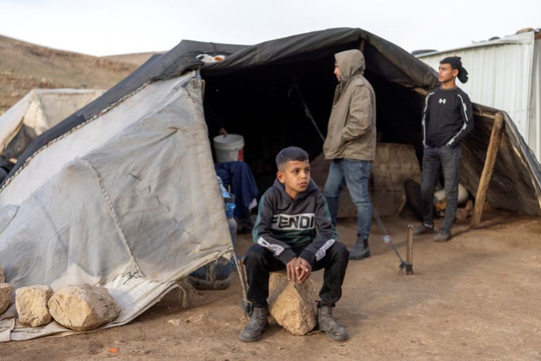 afp_695b9b37bc40-1767611191 Palestinian Bedouin men gather in a tent over looking a newly built Israeli right-wing settler outpost erected inside the land of a Bedouin community of Ras Ein al-Auja near the city of Jericho, in the Israel-occupied Palestinian West Bank on January 1, 2026.