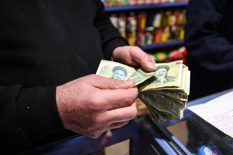 A shop owner counts Iranian banknotes at a store in the capital Tehran on January 7, 2026.