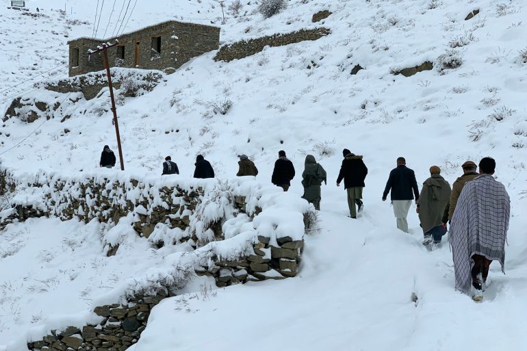 TOPSHOT - Afghan men walk along a snow-covered path in the Dara district of Panjshir province on January 23, 2026.