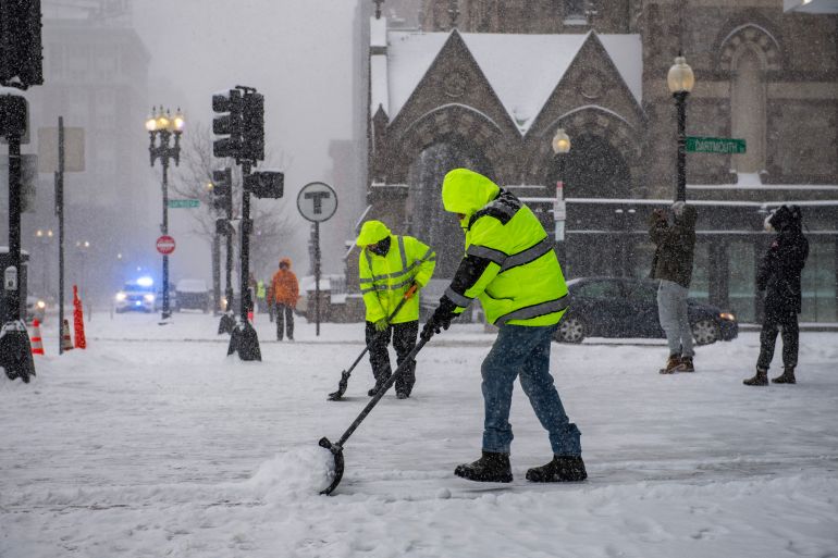 Workers clear snow in Copley Square during a snowstorm in Boston, Massachusetts, on January 25, 2026.