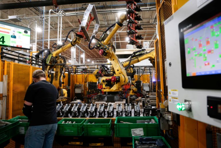 A worker loads production parts at a robot station at the Magna Electric Vehicle Structures Facility that builds battery enclosures for electric (EV) vehicles, in St. Clair, Michigan, U.S., March 26, 2025. REUTERS /Rebecca Cook