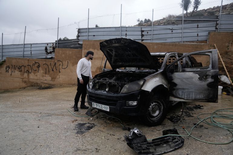 ap_6958a6404bc68-1767417408 A Palestinian man inspects a burnt car that was set ablaze the night before allegedly by local residents who were Israeli settlers, in the town of Huwara near the West Bank city of Nablus, Sunday, Dec. 28, 2025. The graffiti on the wall reads Reveng, regards from Beit Shean". (AP Photo/Majdi Mohammad)