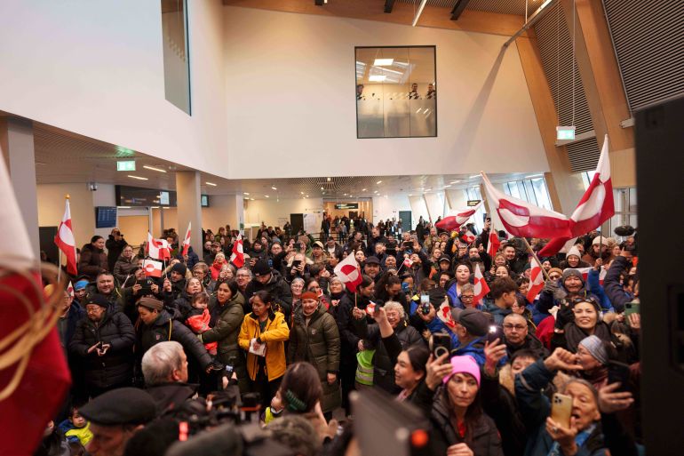 People listen a speech of Greenland Minister for Foreign Affairs and Research Vivian Motzfeldt after her arrival at airport of Nuuk, Greenland, on Tuesday, Jan. 20, 2026. (AP Photo/Evgeniy Maloletka)